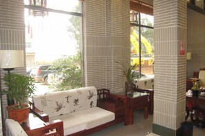 A room with a sofa, a table, and a chair, a lamp, and a potted plant. - Heyuan Boutique Hotel (Shaoguan High-speed Railway Station) (Shaoguan)