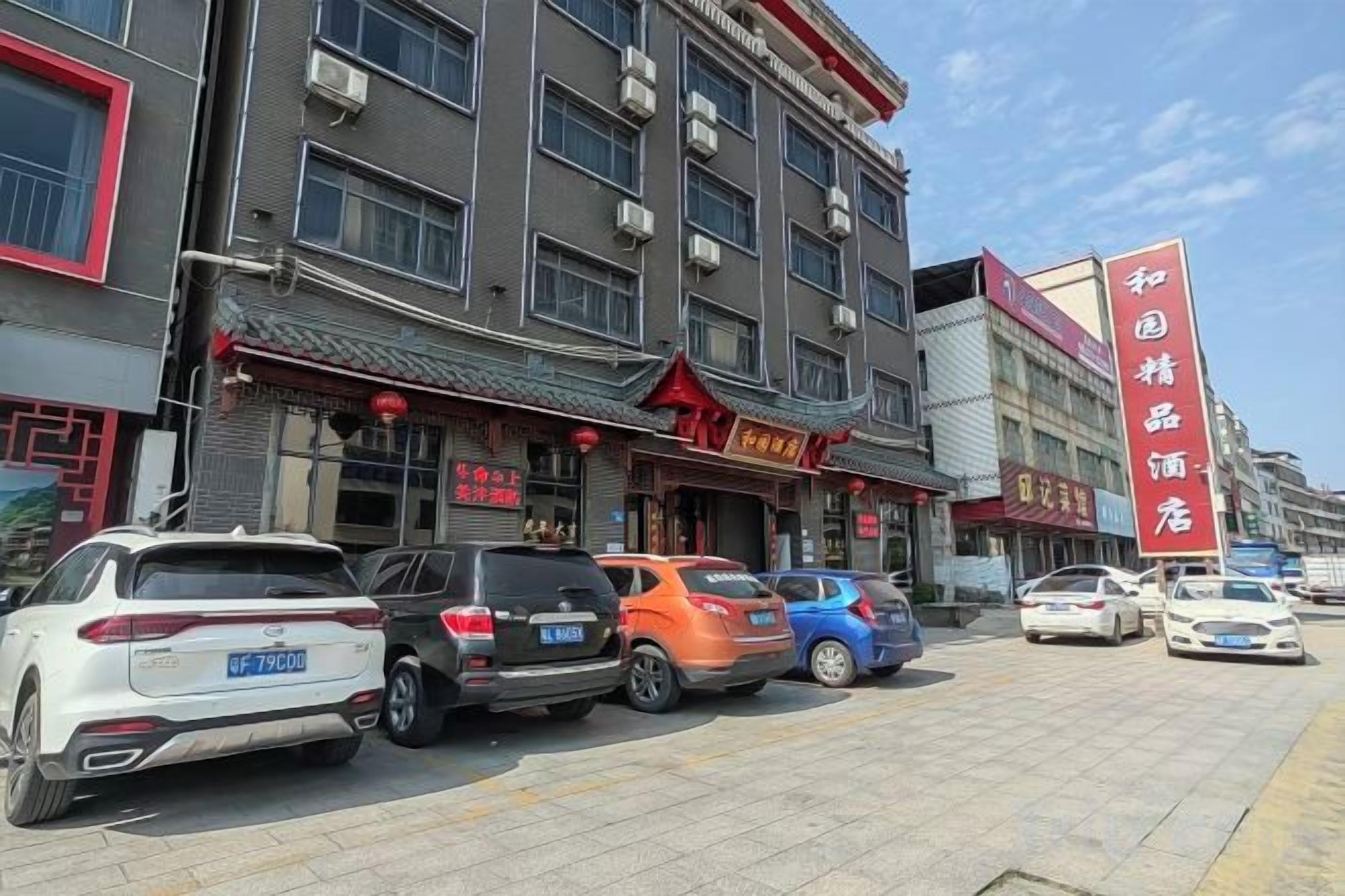 A street with parked cars and a building with multiple shops.