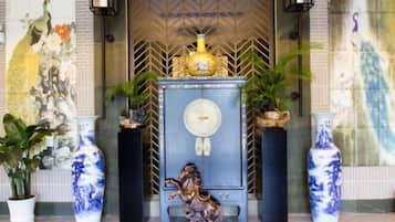 A room with a decorative cabinet, a vase, and a statue.