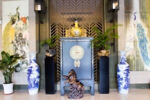 Una habitación con un aparador decorativo, un jarrón y una estatua.