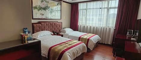 A hotel room with two beds, a large window with curtains, a painting on the wall, and a desk with a chair.