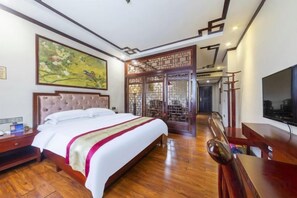A hotel room with a large bed, wooden flooring, a television, and a traditional decorative screen. - Heyuan Boutique Hotel (Shaoguan High-speed Railway Station) (Shaoguan)