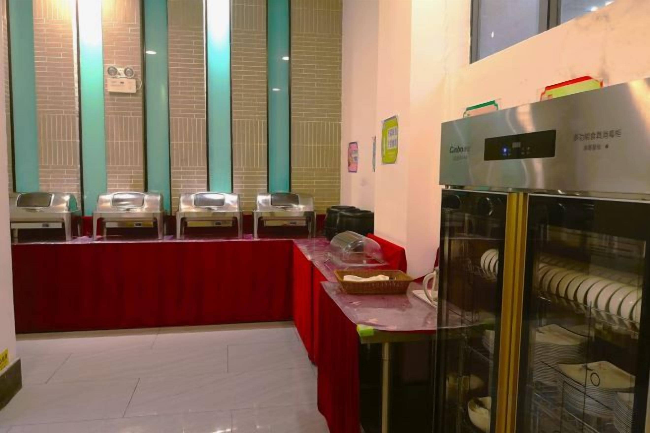 Ein Buffet mit mehreren Servierstationen, einer Glasvitrine und einer roten Tischdecke.