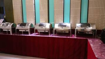 A row of buffet-style food dispensers on a table with a red tablecloth.