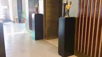 A hallway with black pedestals, a plant, and a vertical striped pattern on the wall.
