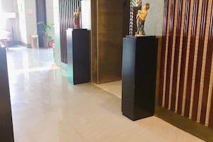 A hallway with black pedestals, a plant, and a vertical striped pattern on the wall.