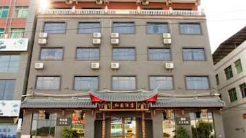 A multi-story hotel with a traditional Chinese architectural entrance, air conditioning units, and a visible storefront.