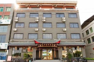 Hotel de varios pisos con entrada de arquitectura china tradicional, unidades de aire acondicionado y un escaparate visible.