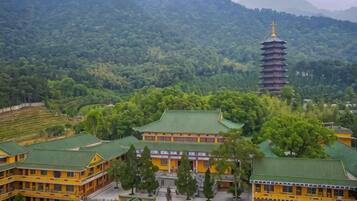 A traditional building with a pagoda-style tower, surrounded by lush greenery and terraced fields.
