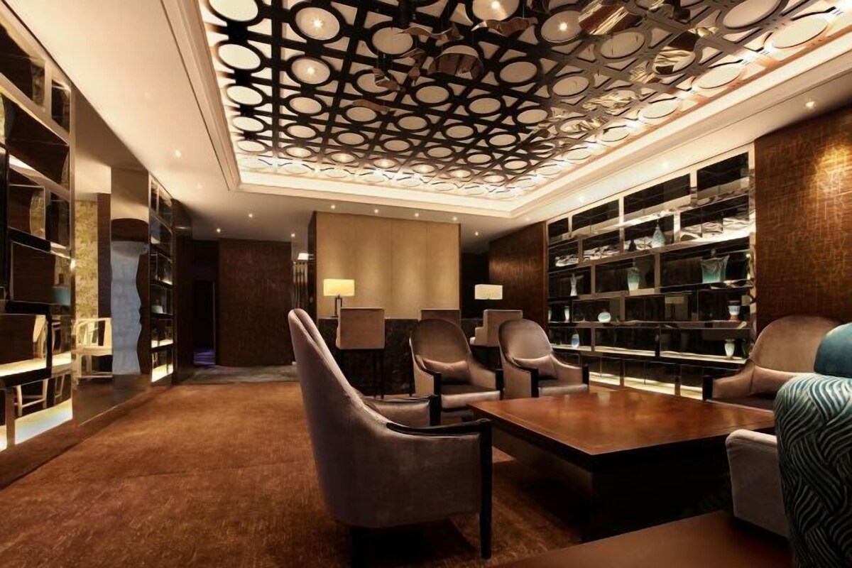 A modern library with leather chairs, a wooden table, and bookshelves.