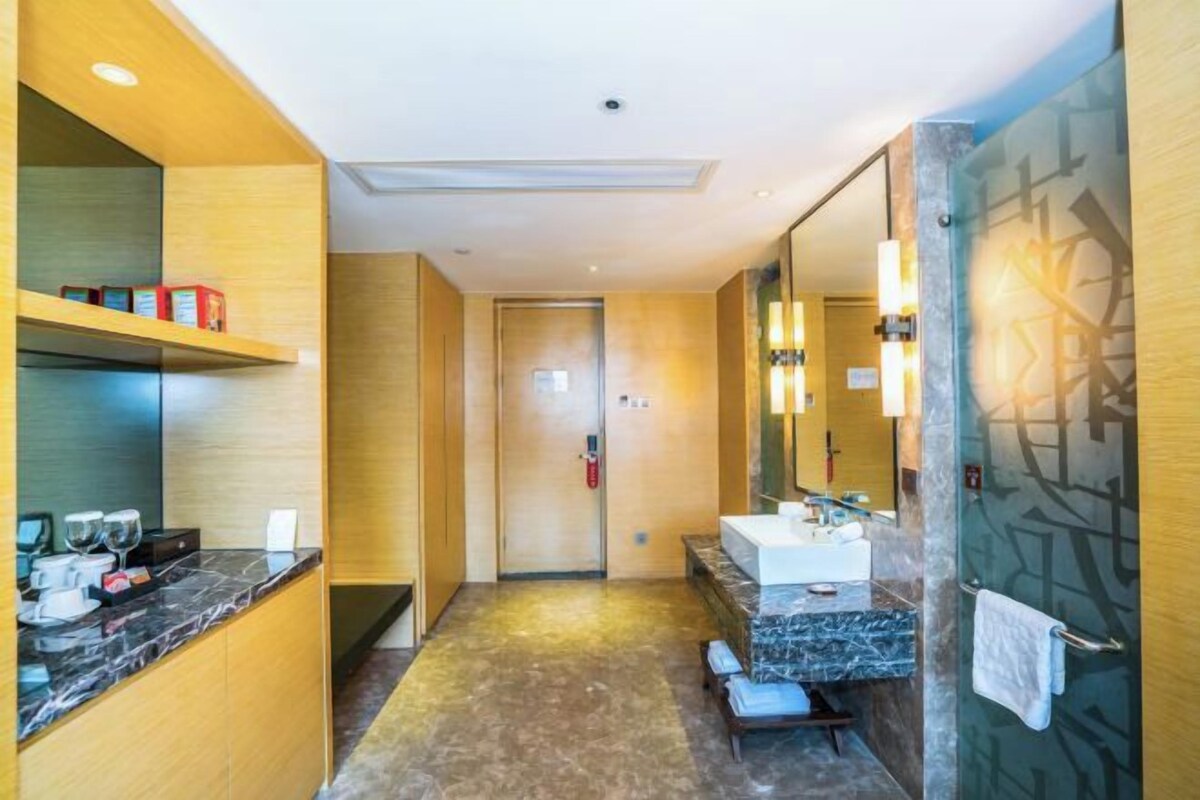 A modern bathroom with a marble countertop, a large mirror, and a shower area.