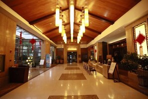Un hall d’hôtel avec un plafond en bois, un comptoir d’accueil et des plantes en pot.