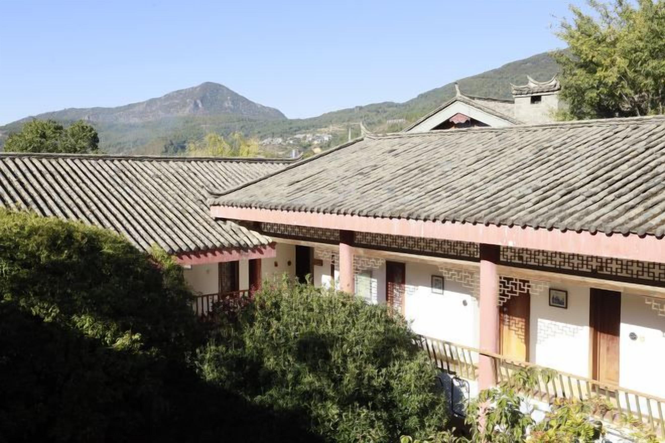 A traditional building with a tiled roof, a balcony, and a mountain backdrop.