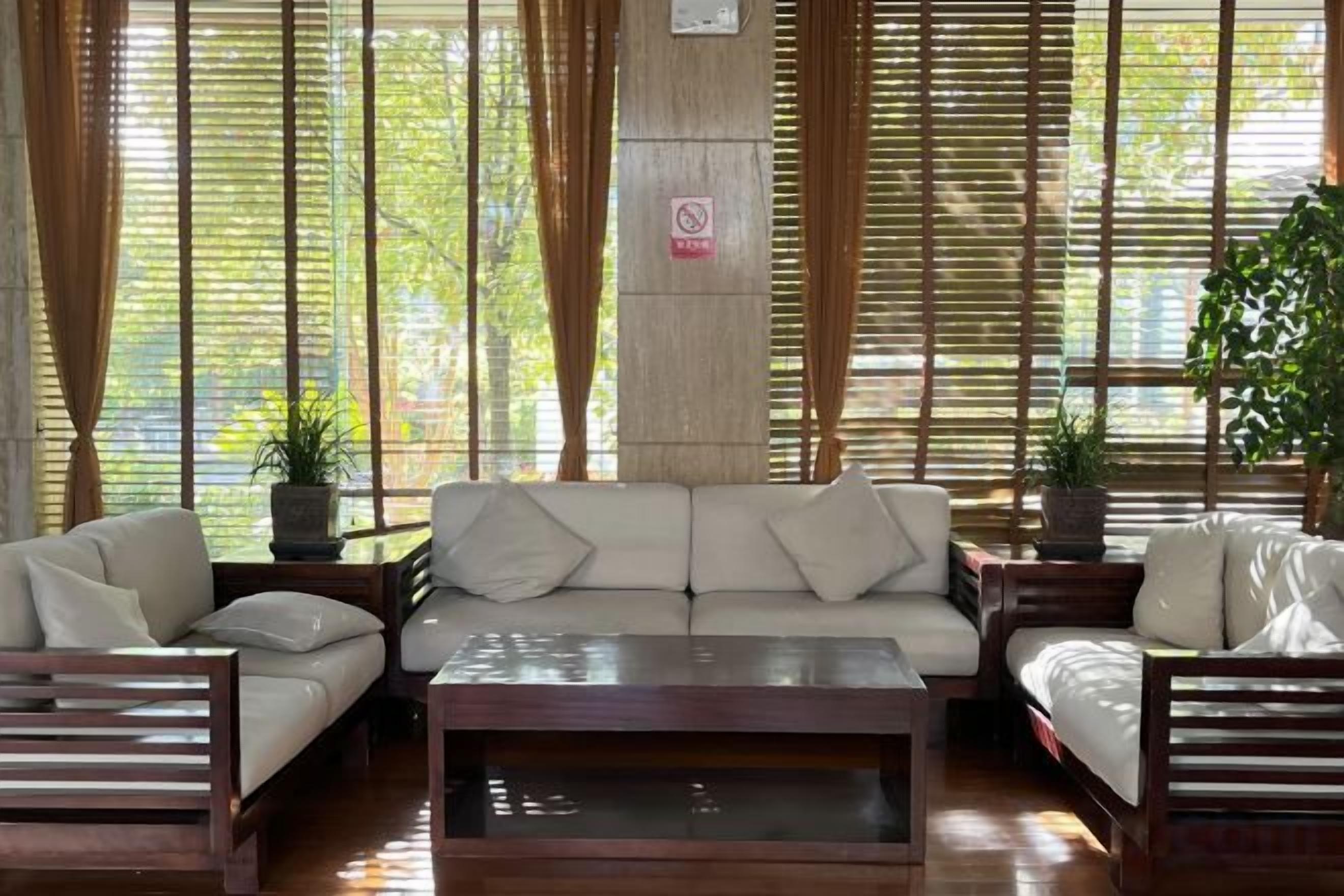 A room with a sofa set, a coffee table, and a potted plant.
