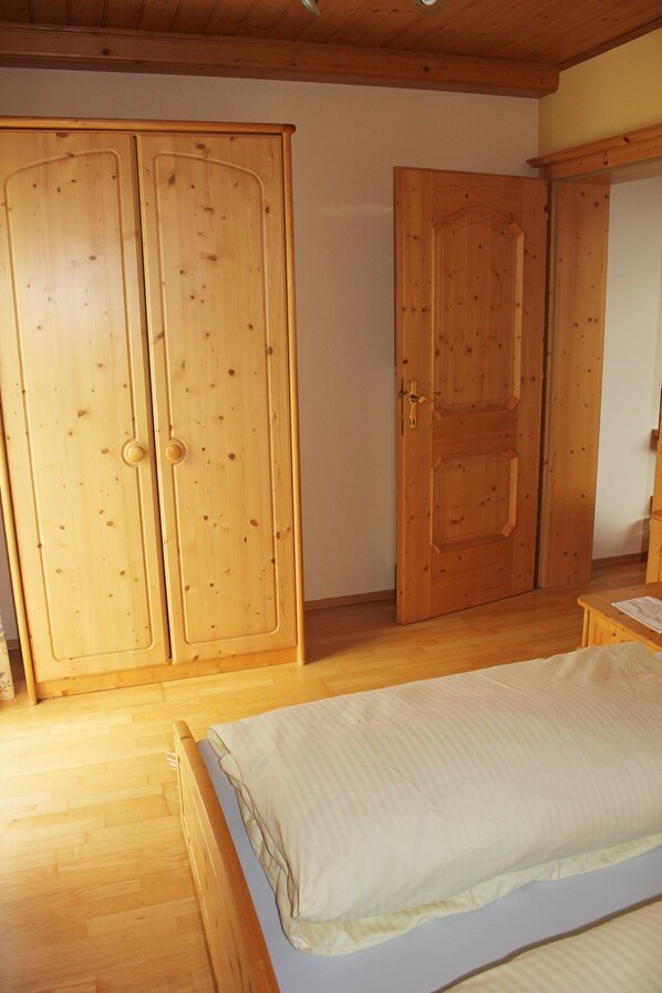 Un dormitorio con una cama de madera, un armario y una puerta.