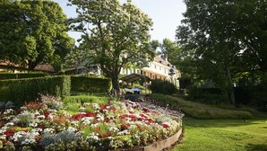 A garden with a gazebo, a large tree, and a building in the background.