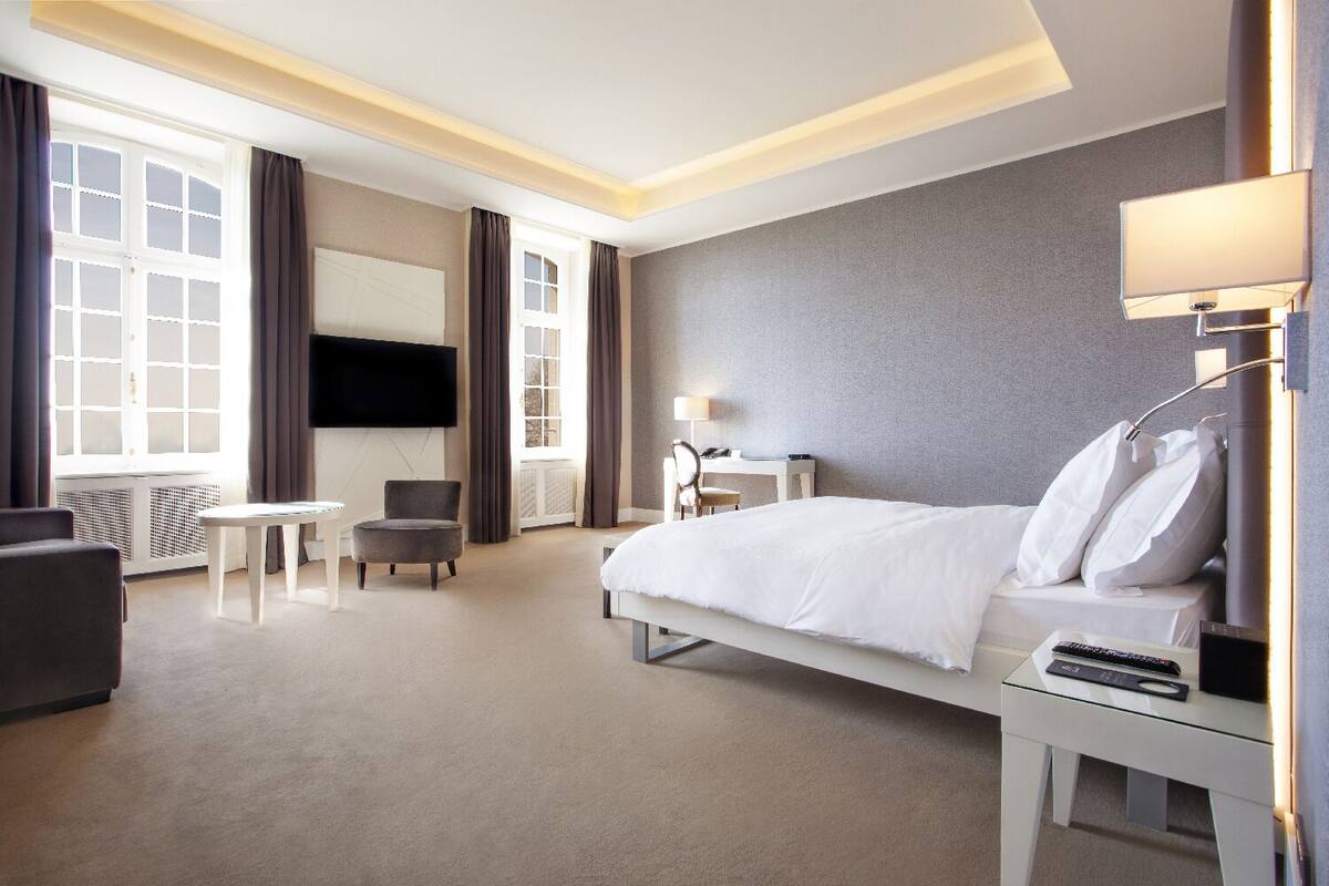 Una habitación de hotel con una cama, un escritorio, una silla, un televisor y una lámpara.