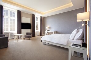 Une chambre d’hôtel avec un lit, un bureau, une chaise, une télévision et une lampe.