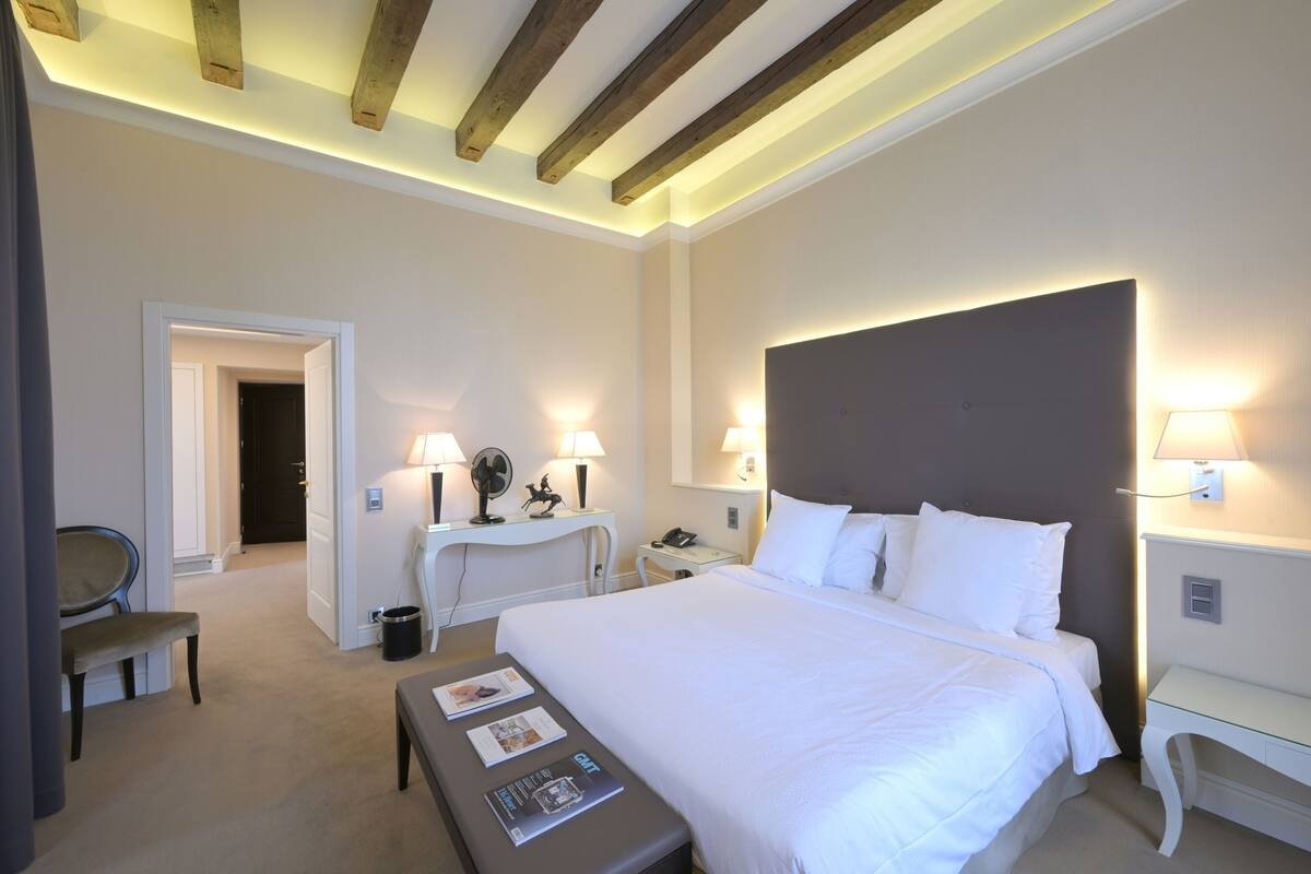 Una habitación de hotel con una cama grande, lámparas de noche, un escritorio y una silla.
