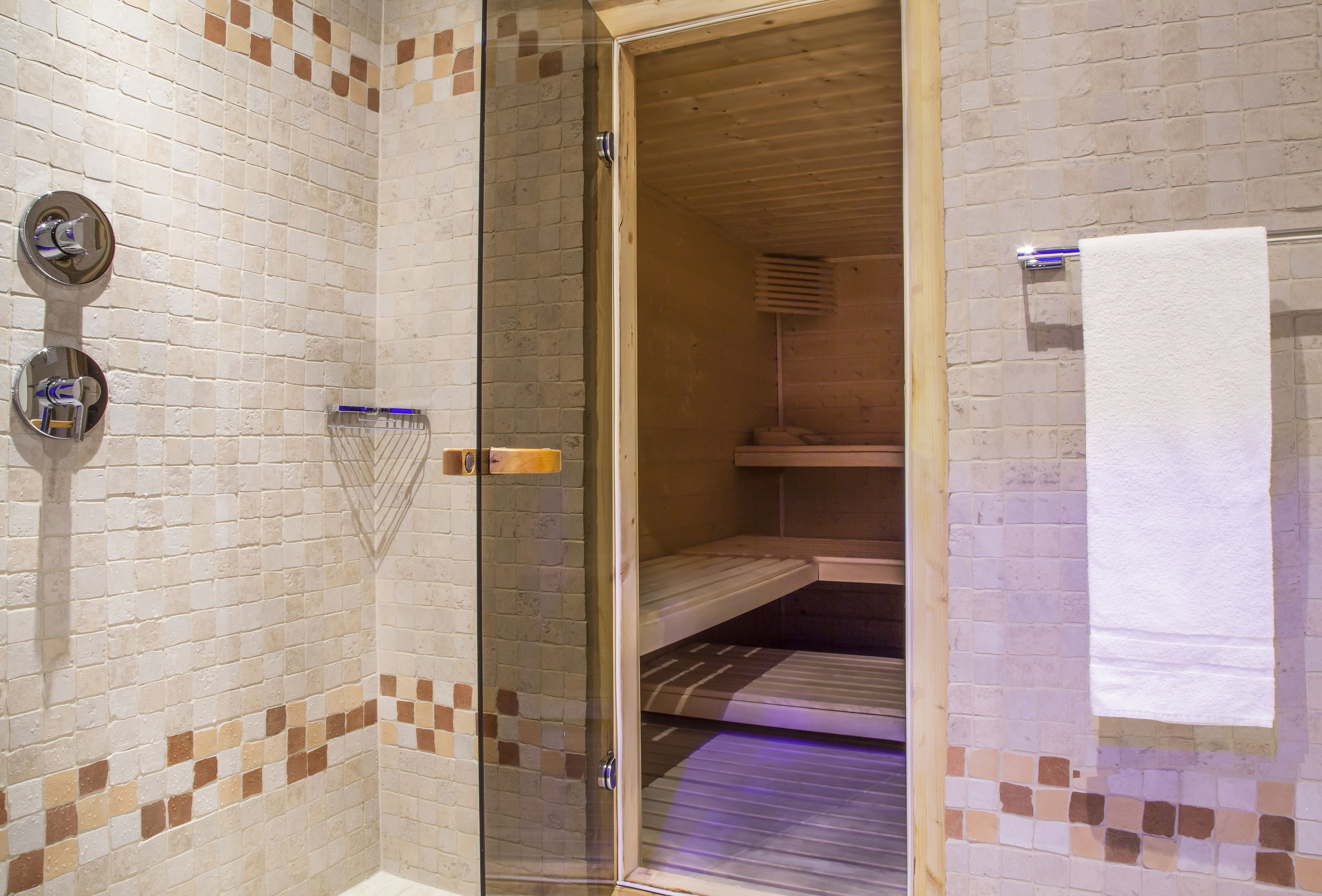 A shower area with a glass door, tiled walls, and a towel rack.