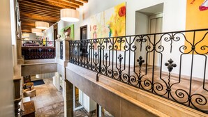 A multi-level interior with a staircase, a dining area, and a large abstract painting on the wall.