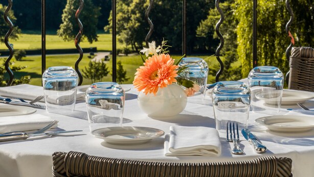 A dining table set outdoors with a view of a mountainous landscape.