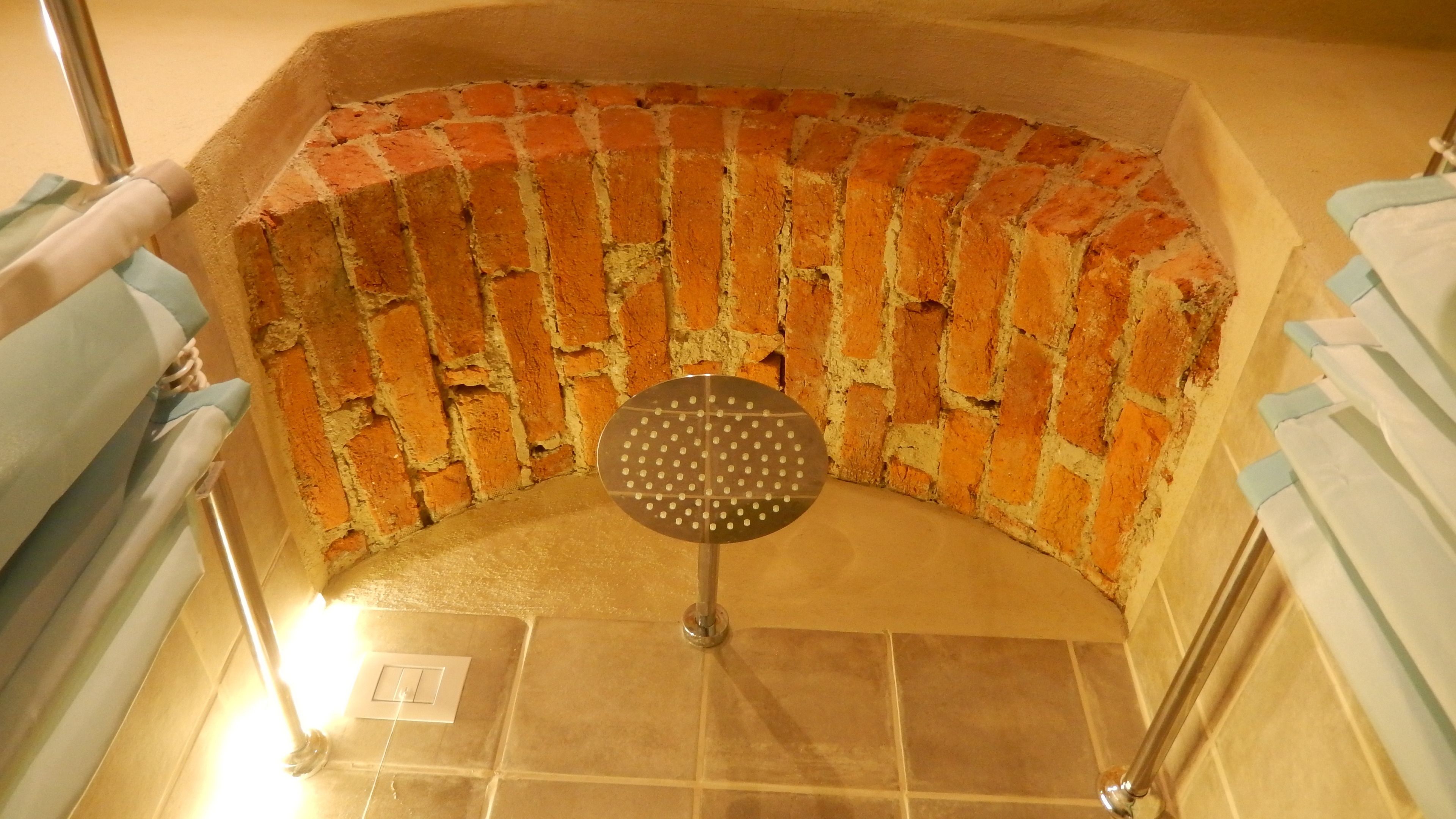Un espace douche avec un sol carrel é et un mur en briques.
