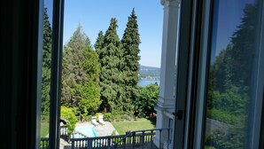 A view from a balcony with a pool, surrounded by trees and a lake. - White Lilac romantic B&B adults only (Arona)