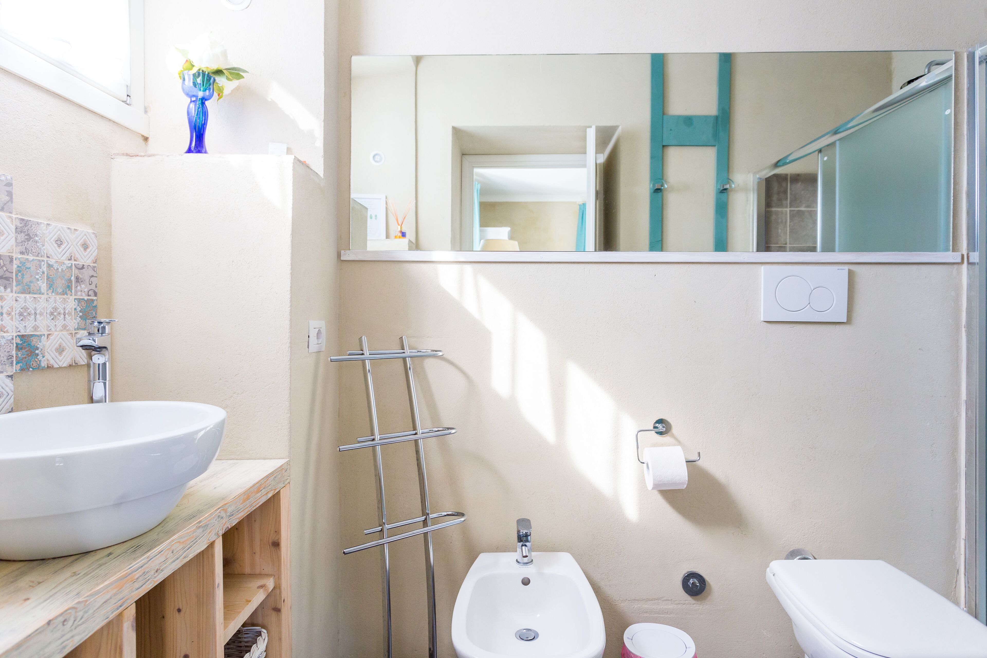 Un baño con un lavamanos grande de color blanco, un lavabo pedestal pequeño, un inodoro y un espejo sobre el lavamanos.