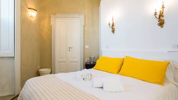 A hotel room with a bed, a white door, and a nightstand with a lamp.
