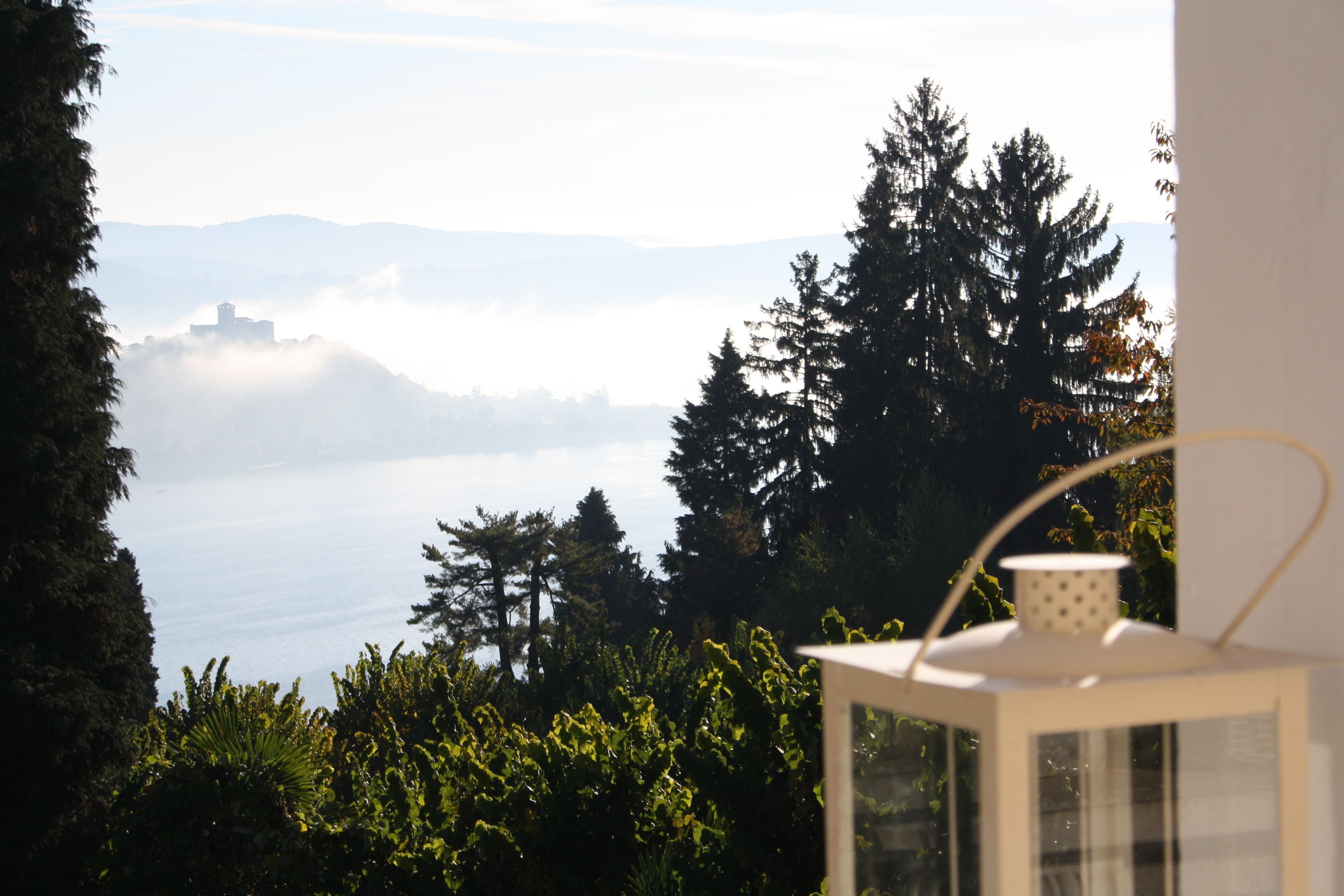 A view from a window overlooking a body of water, with a distant building partially obscured by fog.
