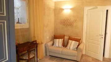 A room with a striped sofa, a wooden chair, a table, and a geometric wall decoration.