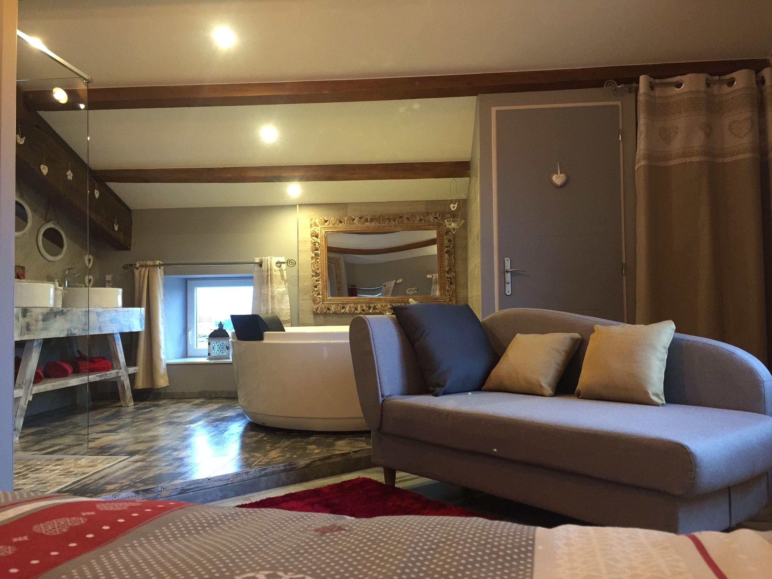 Un salon avec un canapé, un miroir, une baignoire et un escalier.