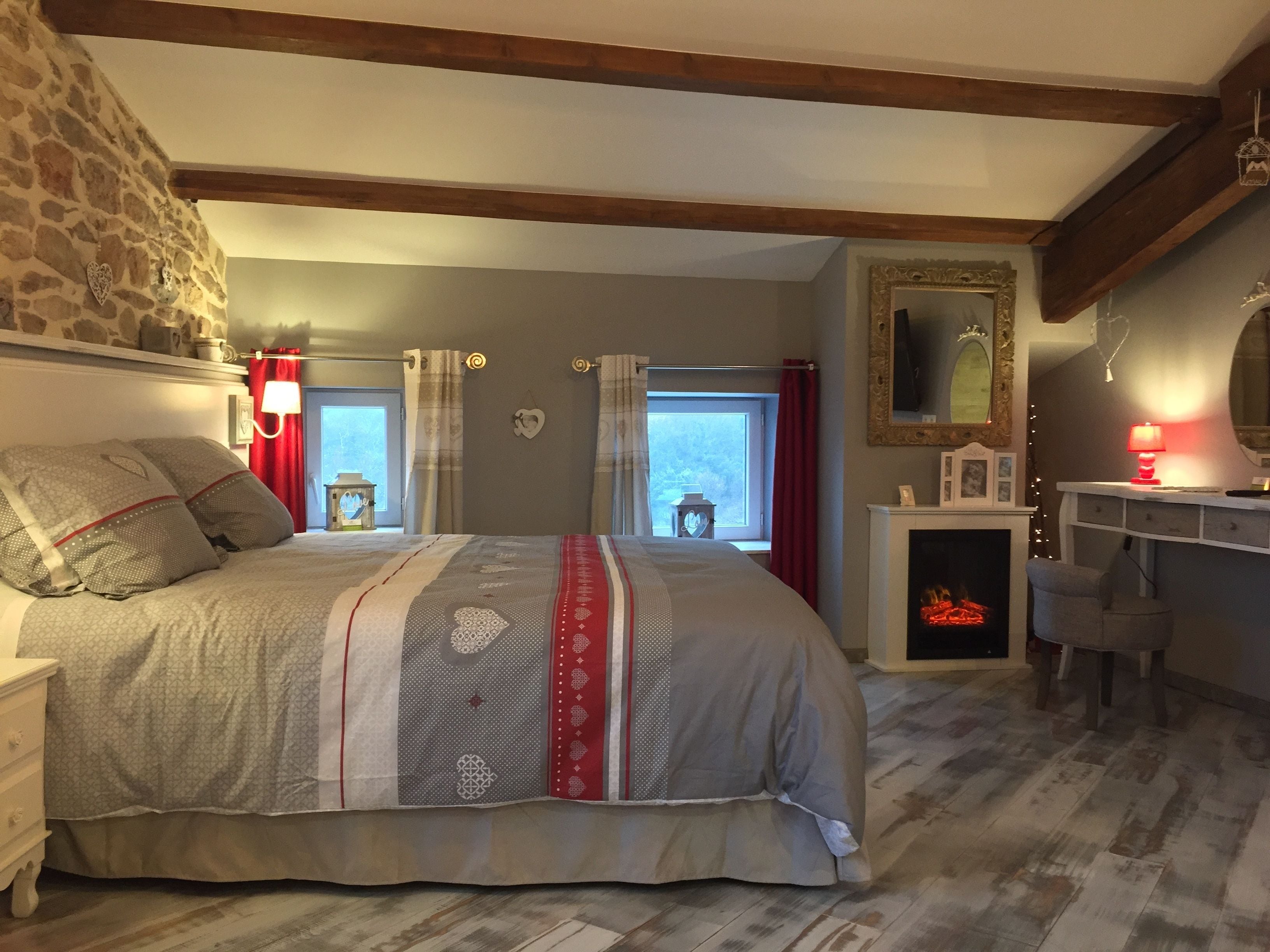 Un dormitorio con una cama grande, una pared de piedra, una chimenea y un espejo.