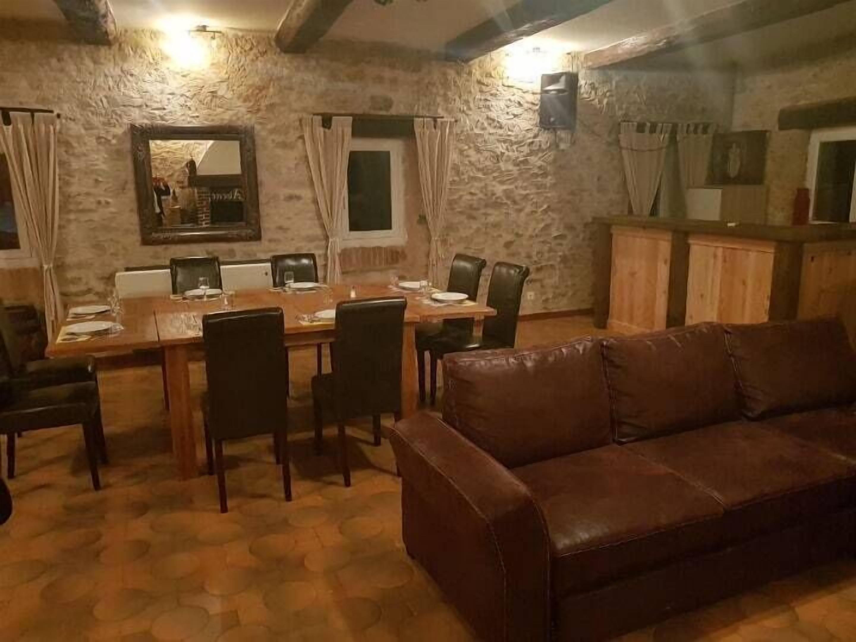 Un coin repas avec un mur en pierre, une table en bois et un canapé en cuir.