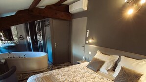 Un dormitorio con una cama grande, una zona de estar con una silla, una bañera y una ducha.