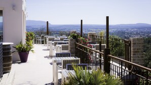 Una terraza con mobiliario exterior, plantas en macetas y vistas al paisaje.