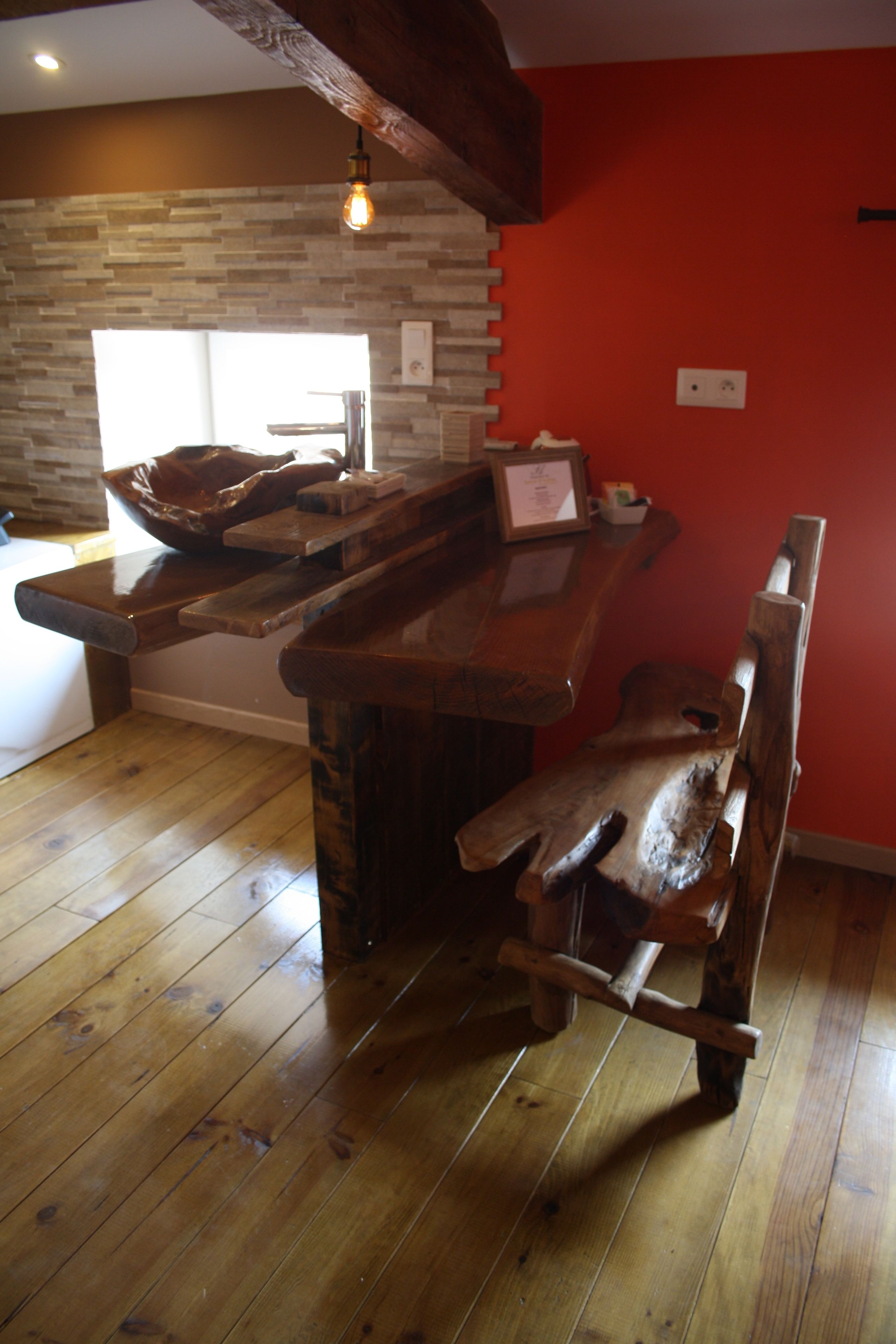 Una cocina rústica con una barra de madera, una silla de madera y una lámpara colgante.