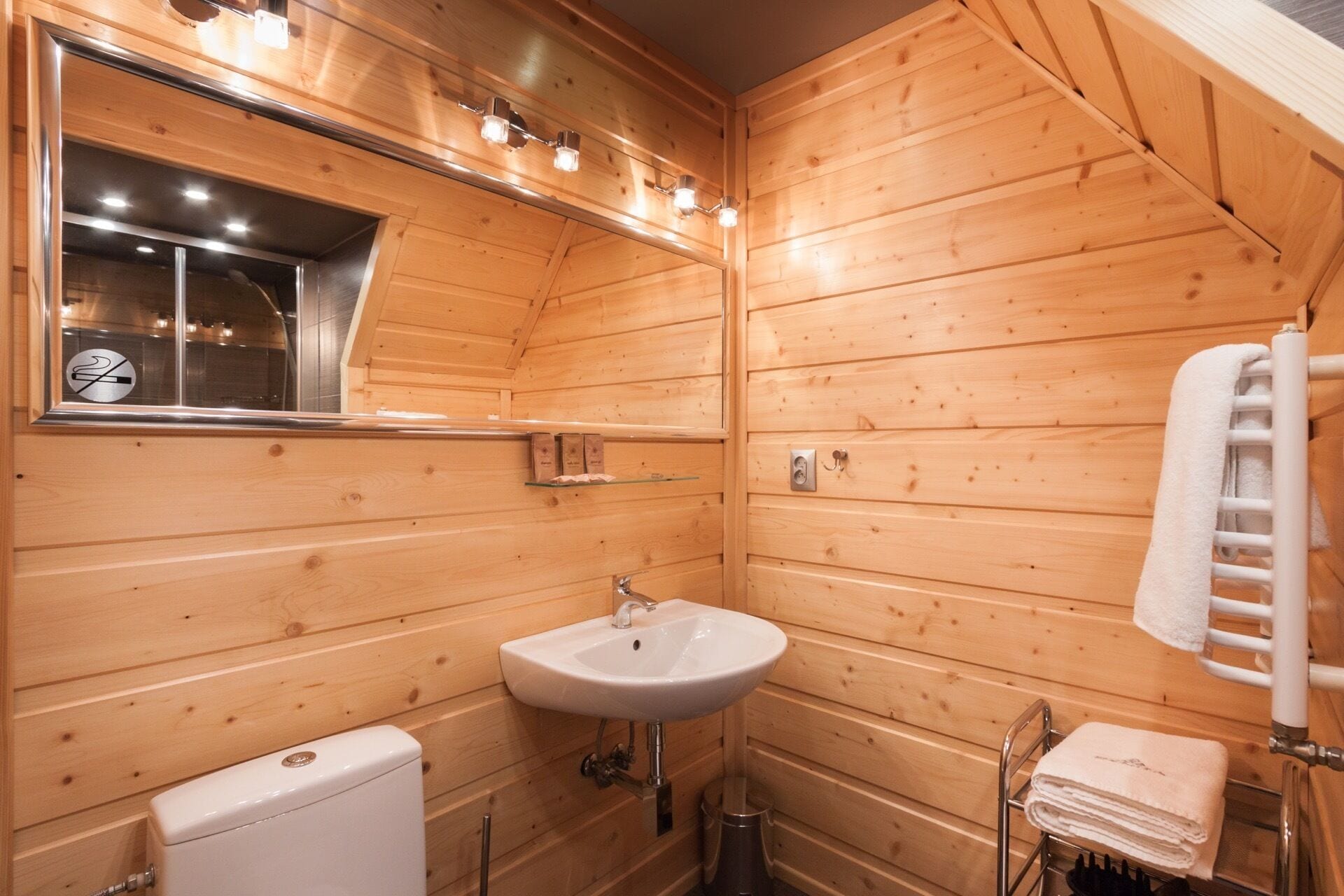 A wooden cabin bathroom with a sink, toilet, and a towel rack.