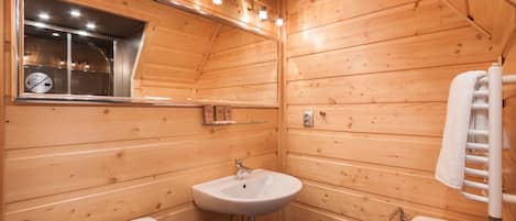 A wooden cabin bathroom with a sink, toilet, and a towel rack.
