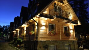 Une maison en bois avec un balcon, des fondations en pierre et des jardinières.