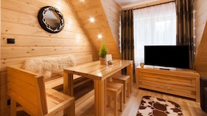 Un intérieur en bois comprenant un coin repas, un téléviseur et une fenêtre avec des rideaux.