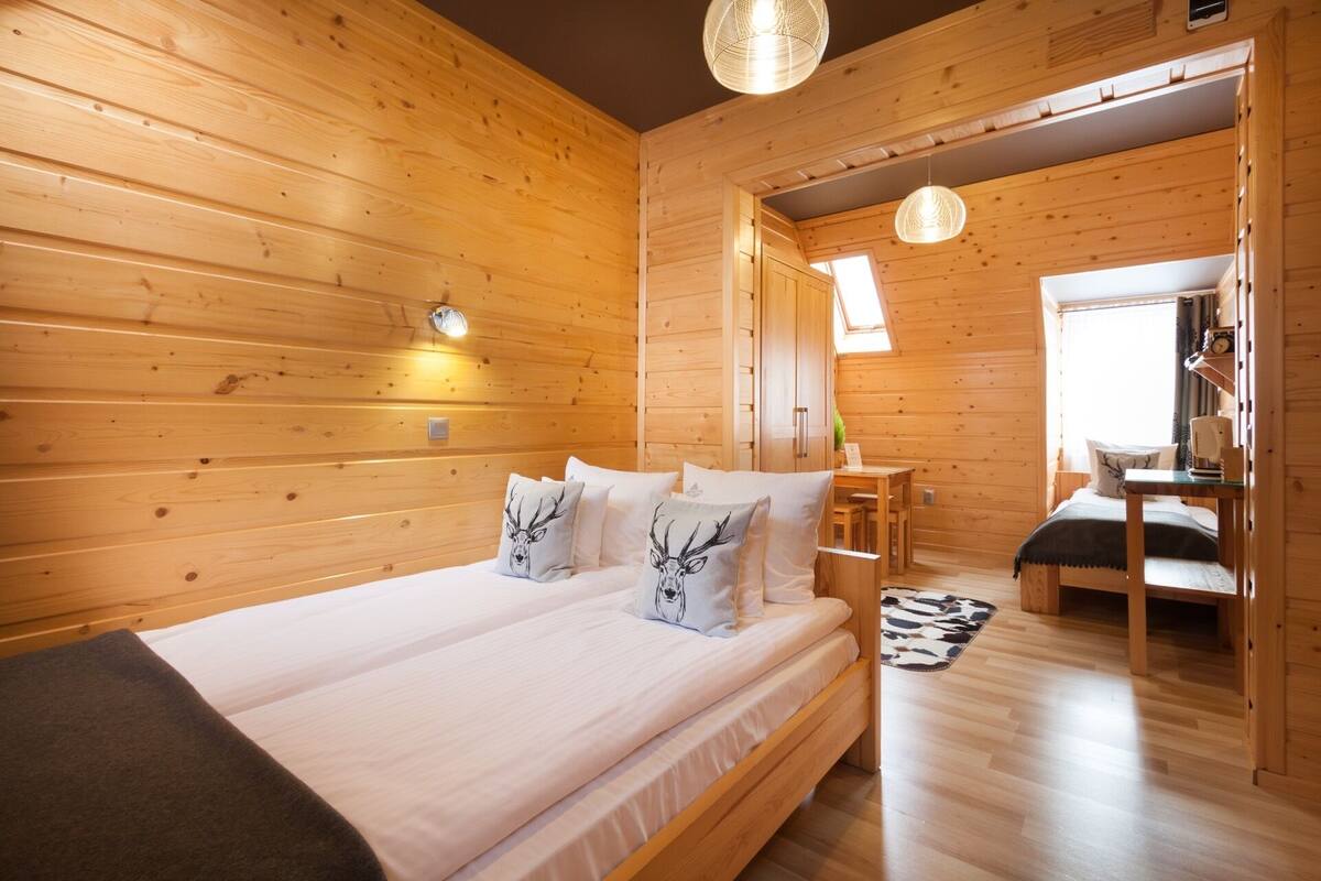 Een houten slaapkamer met een bed, nachtkastjes en een klein bureau.