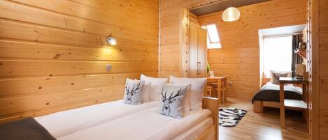 A wooden cabin bedroom with a bed, bedside tables, and a small desk.