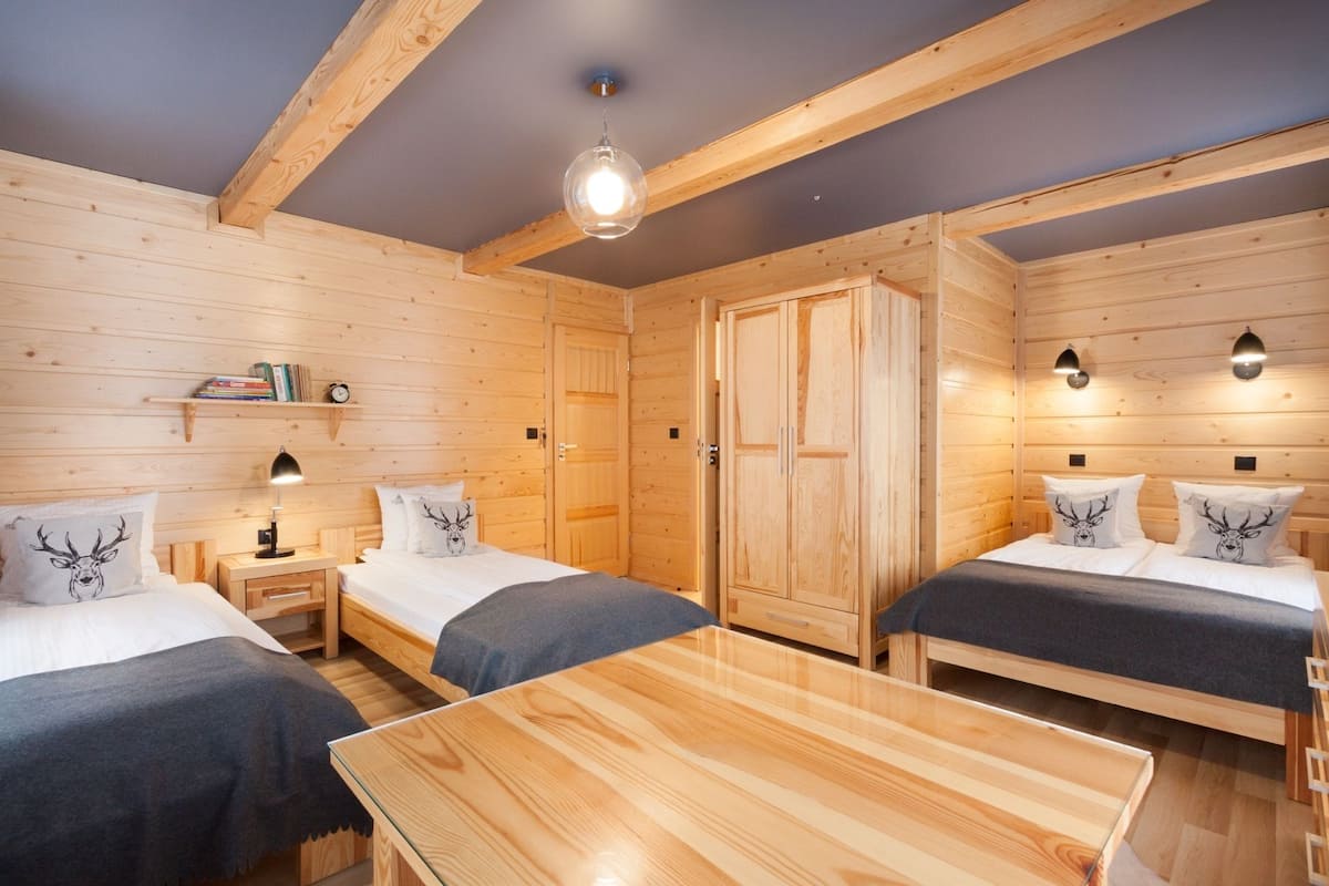 Een houten kamer met twee bedden, een tafel en een kledingkast.