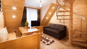 Une pièce chaleureuse avec un décor intérieur en bois, un canapé, une télévision, une table à manger et un escalier en colimaçon.