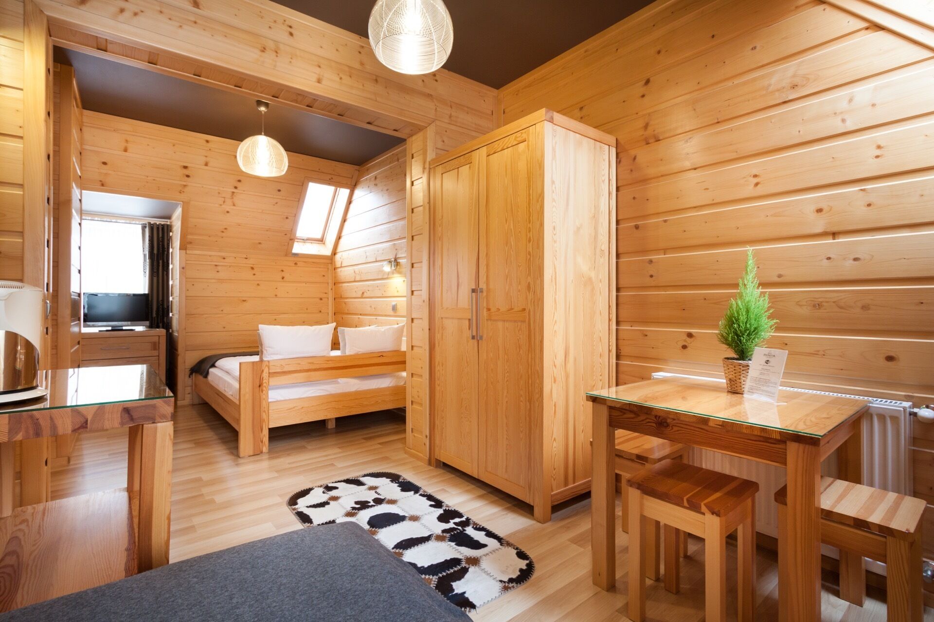 A cozy cabin interior with wooden walls, a bunk bed, a small table, and a desk.