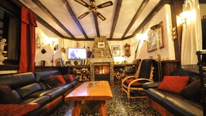 Una sala de estar acogedora con chimenea, sofás de cuero, una mesa de centro de madera y un ventilador de techo.