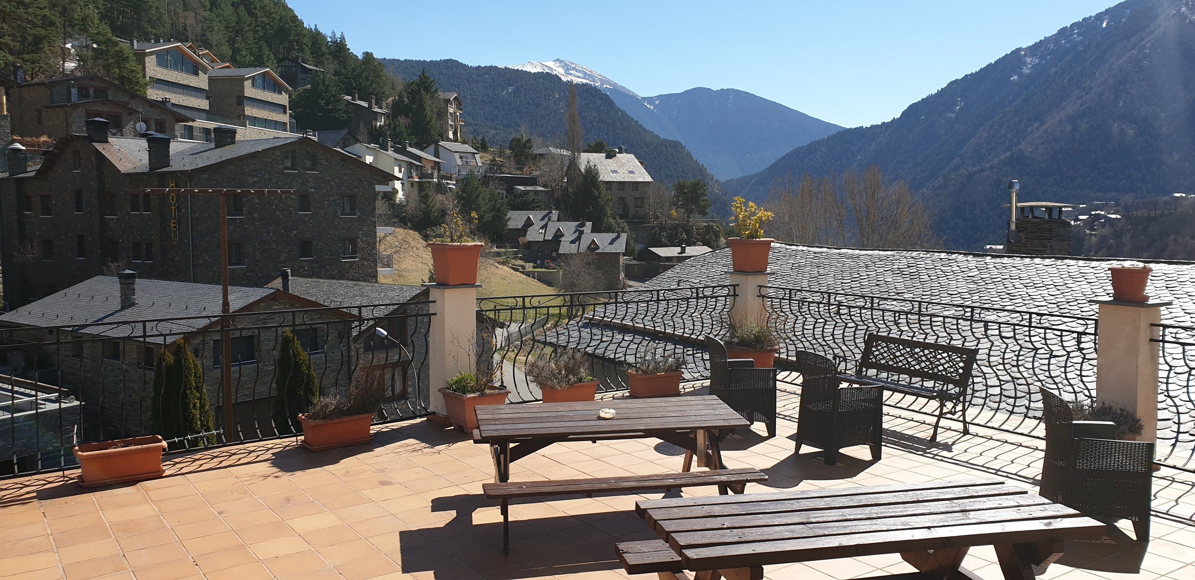 A terrace with outdoor seating, potted plants, and a view of a mountain range.