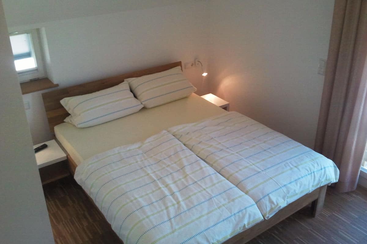 A single bed with a wooden headboard, a bedside table, and a wall-mounted light.